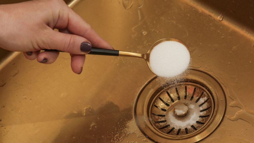 pouring a cup of baking soda on the drain of a clogged sink
