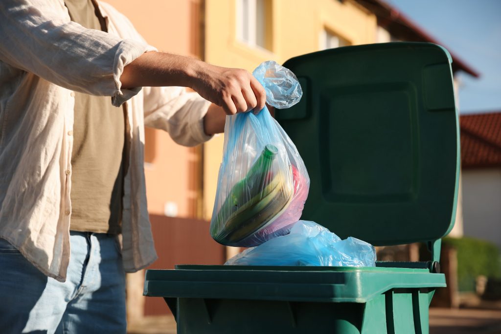 putting trash inside a trash bin
