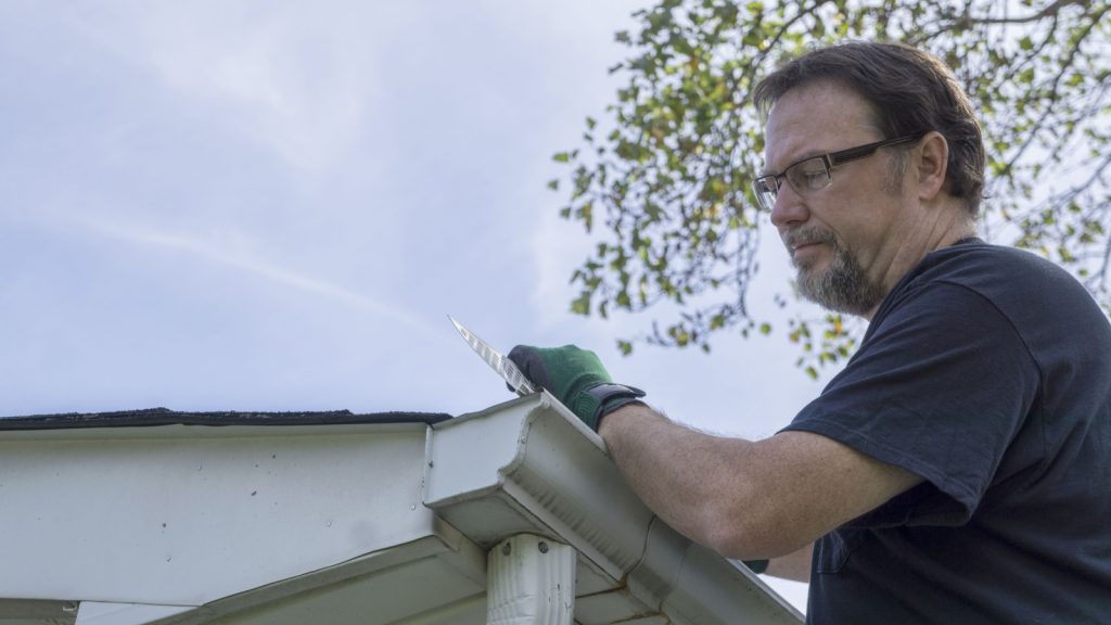 a person installing plastic gutter guards on a older home