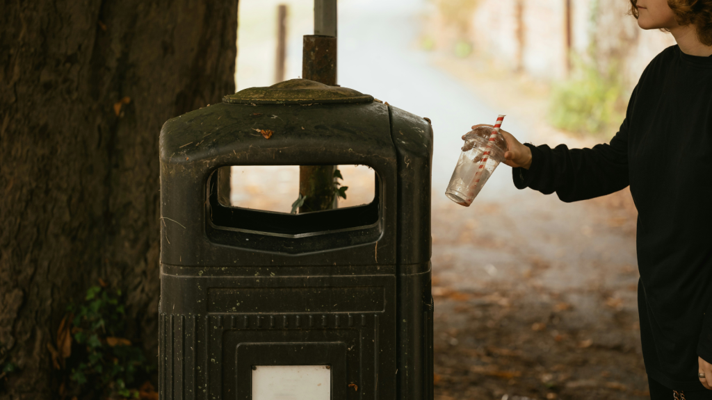 putting plastic cup into trash bin
