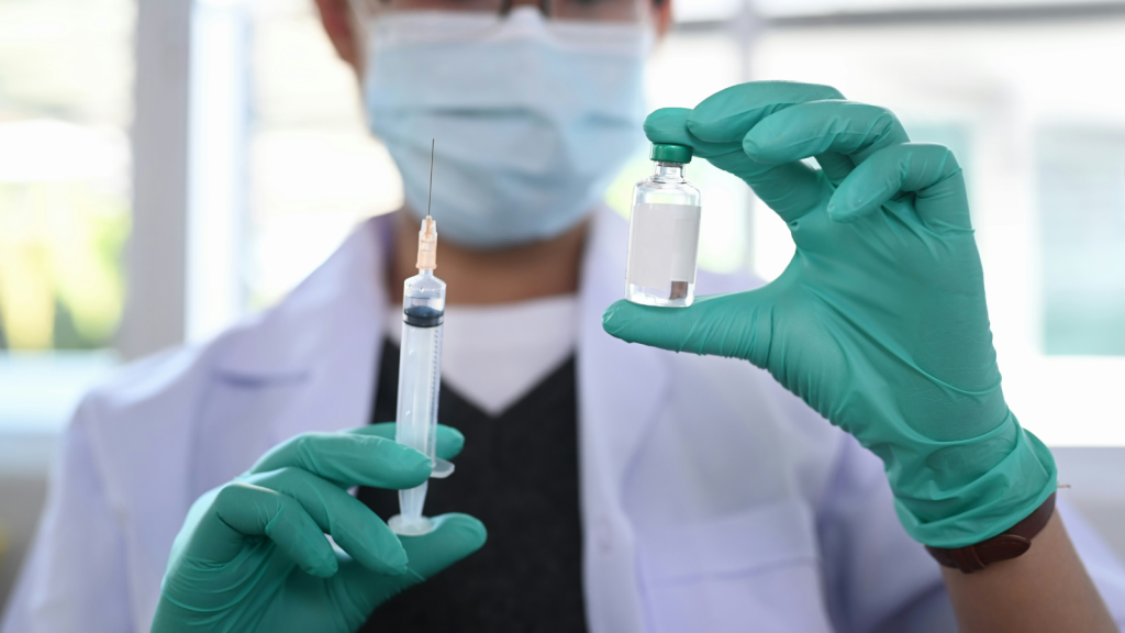 a medical practitioner holding a vial and a syringe
