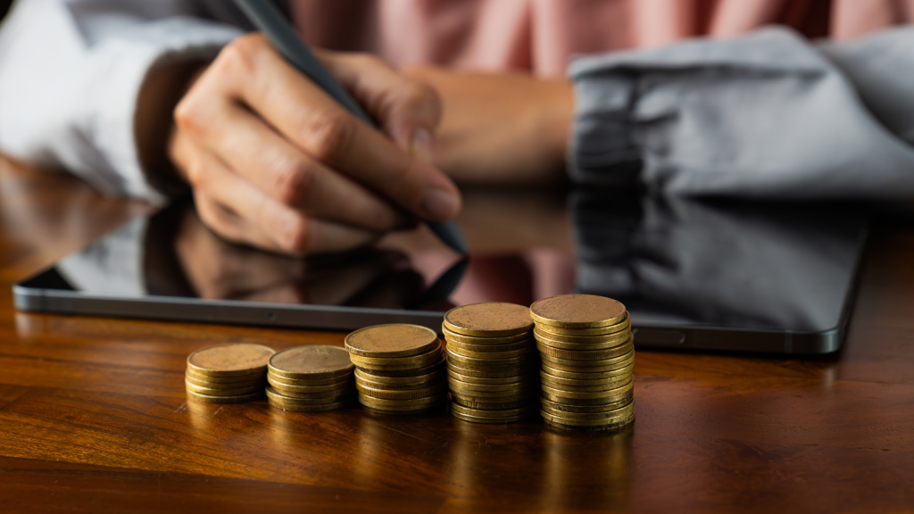 Using a smartphone or tablet with a heap of coins money in the front