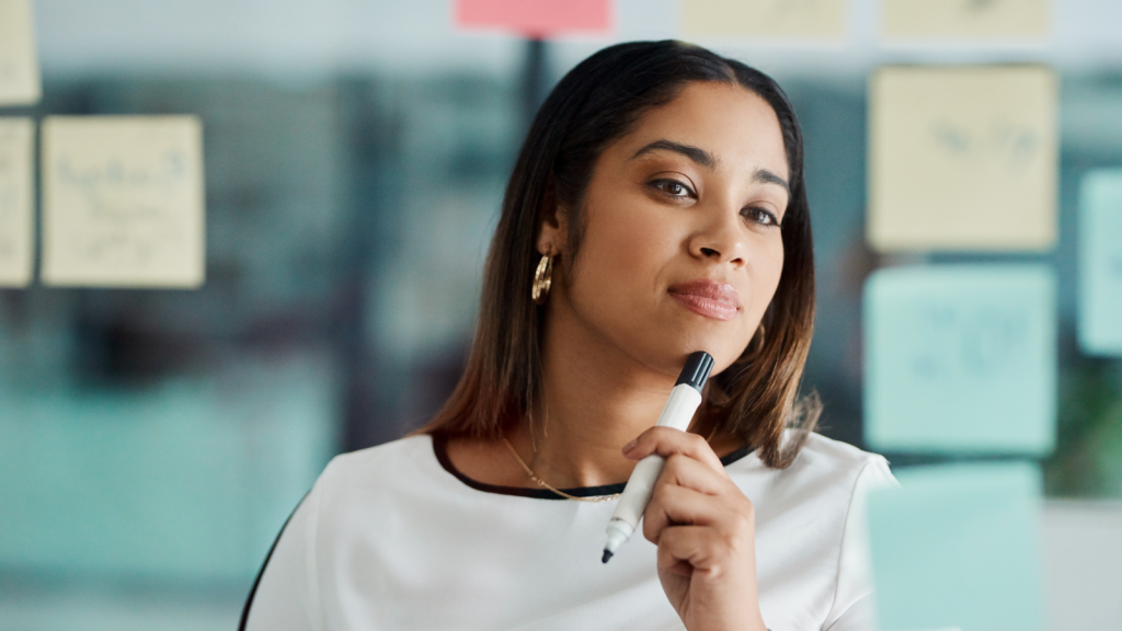 Woman brainstorming with notes on a glass wall in an office