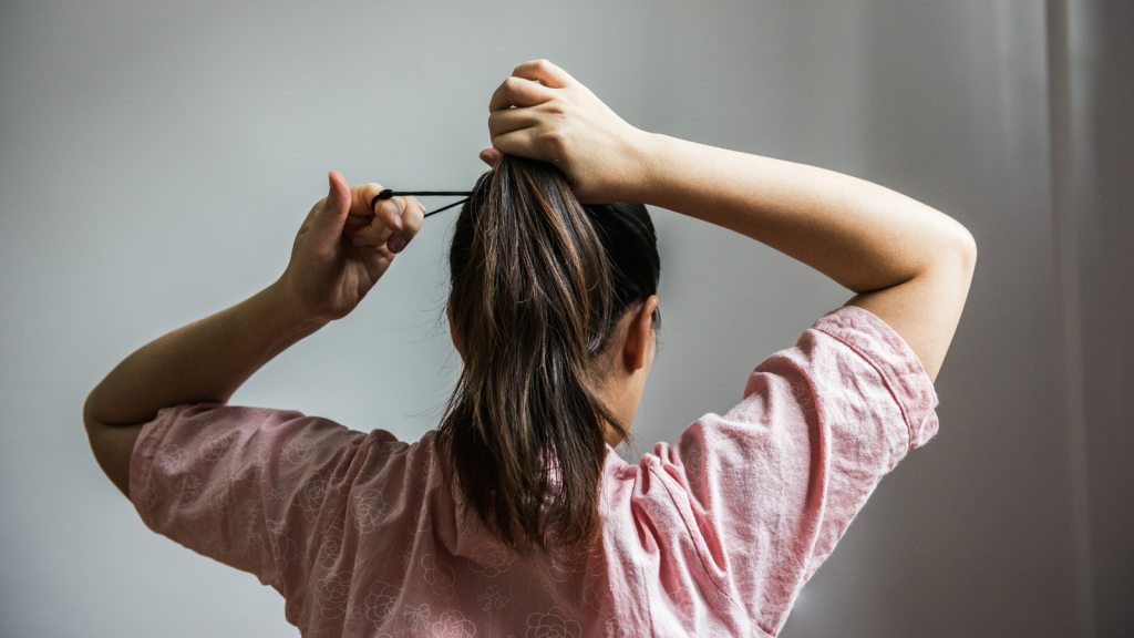 Woman collecting hair in a ponytail