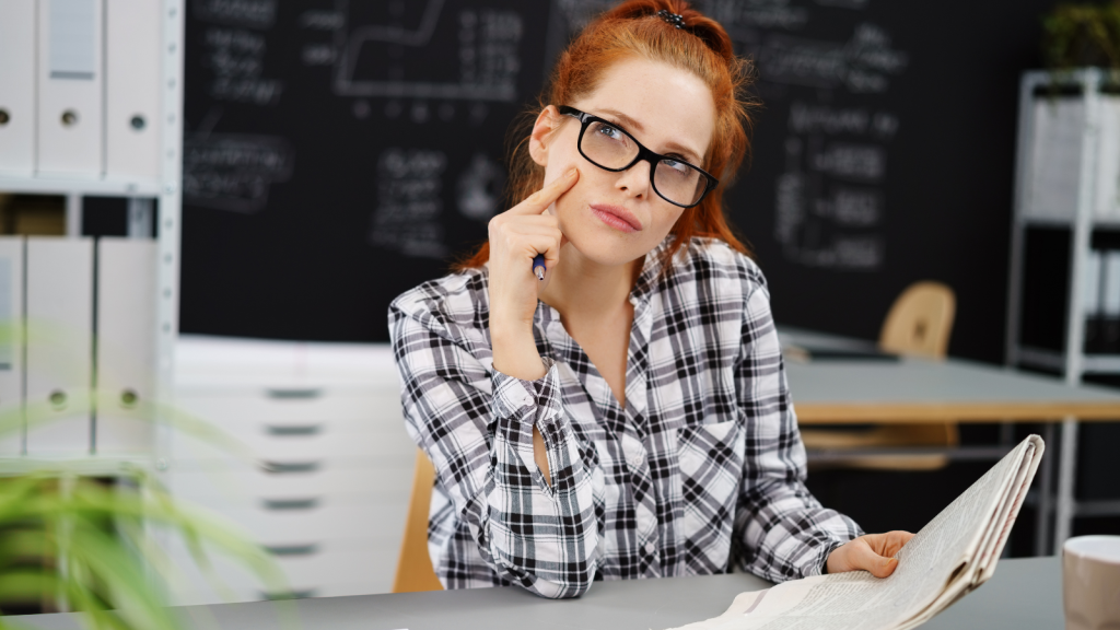 Woman in eyeglasses and flannel shirt thinking about her notes