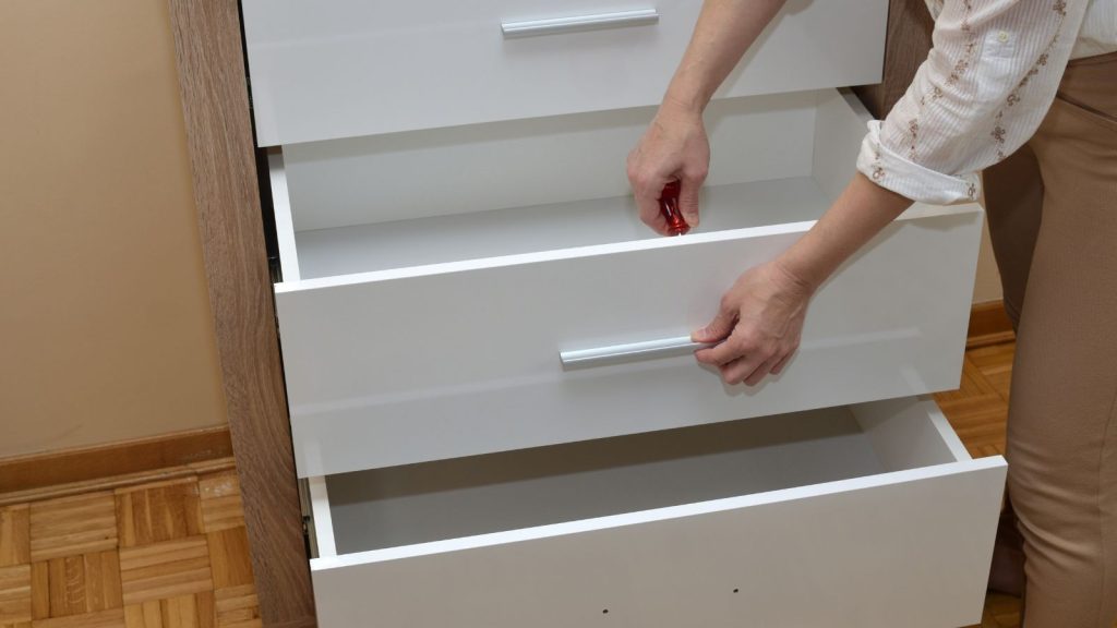 Woman's hands attaching a handle of a drawer