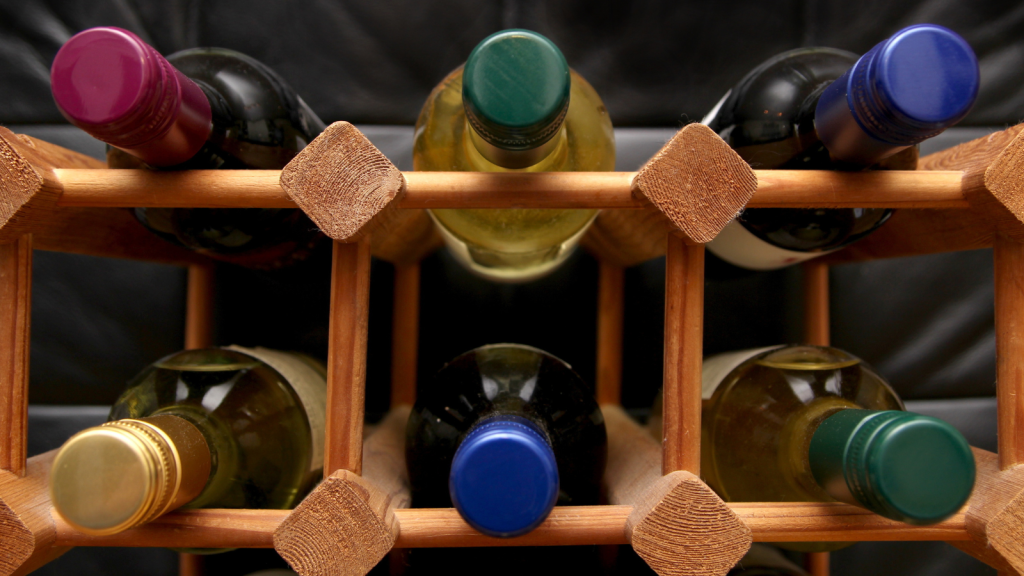 Wooden wine rack with various color bottle tops on dark background