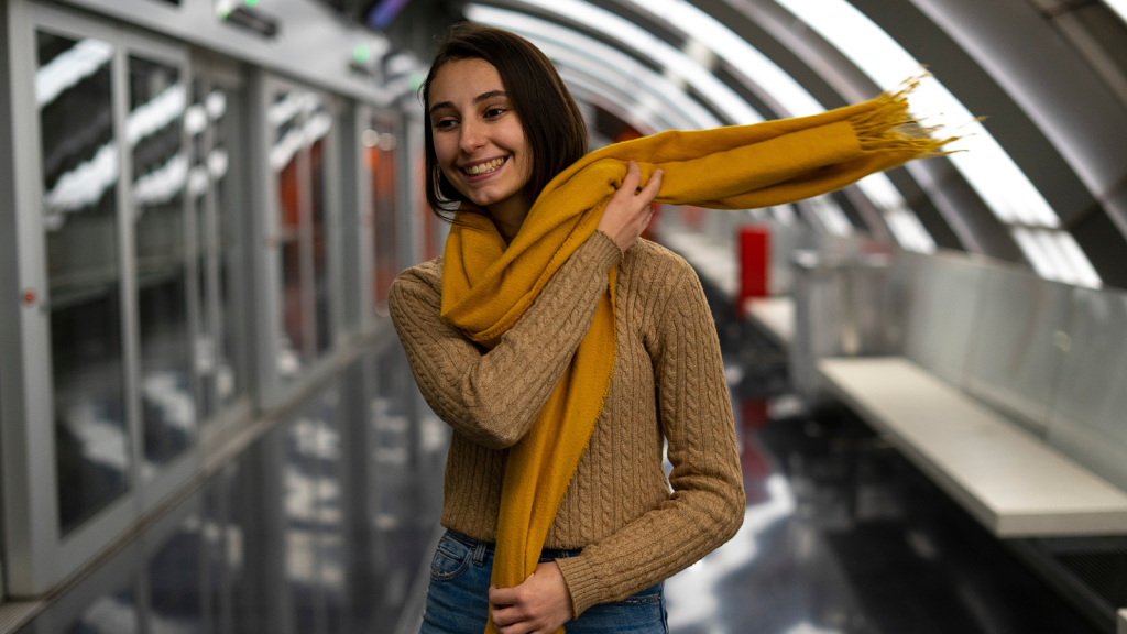 Young woman putting on a yellow scarf