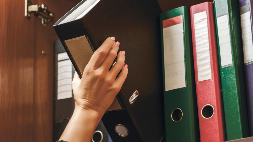 a woman officer pick a binder of document on the row of file folders