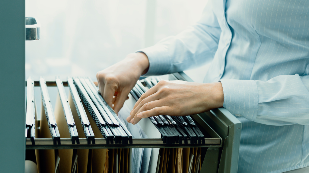 female office clerk searching files and paperwork in the filing cabinet