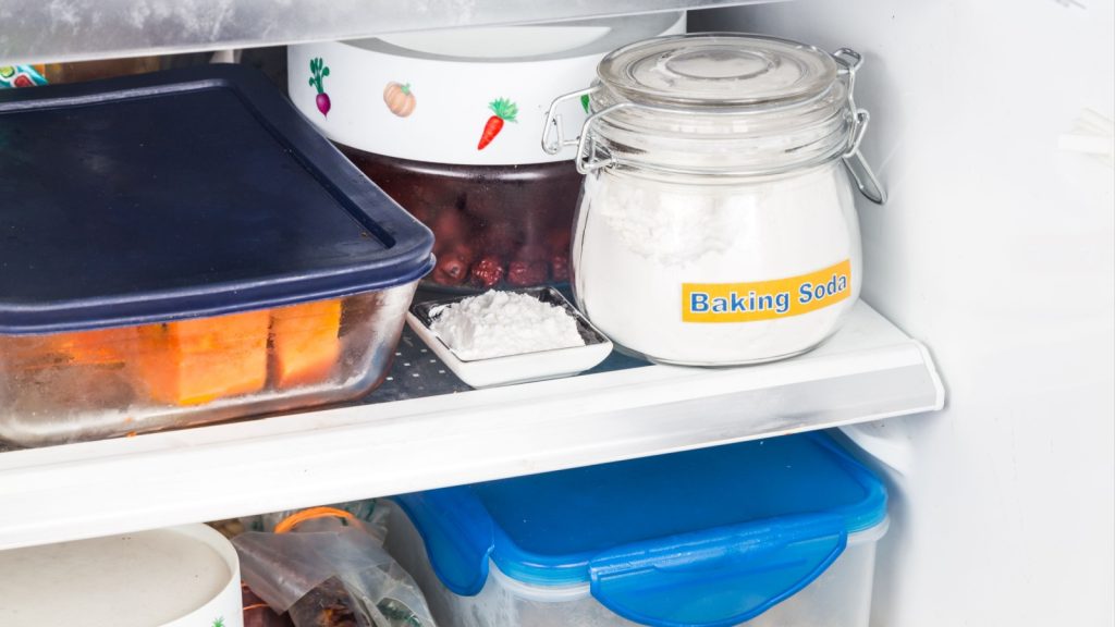 Refrigerator shelf with a jar of baking soda and food containers.