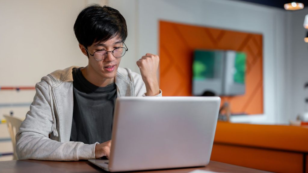 Man in casual clothes and eyeglasses is showing his clenched fist while working