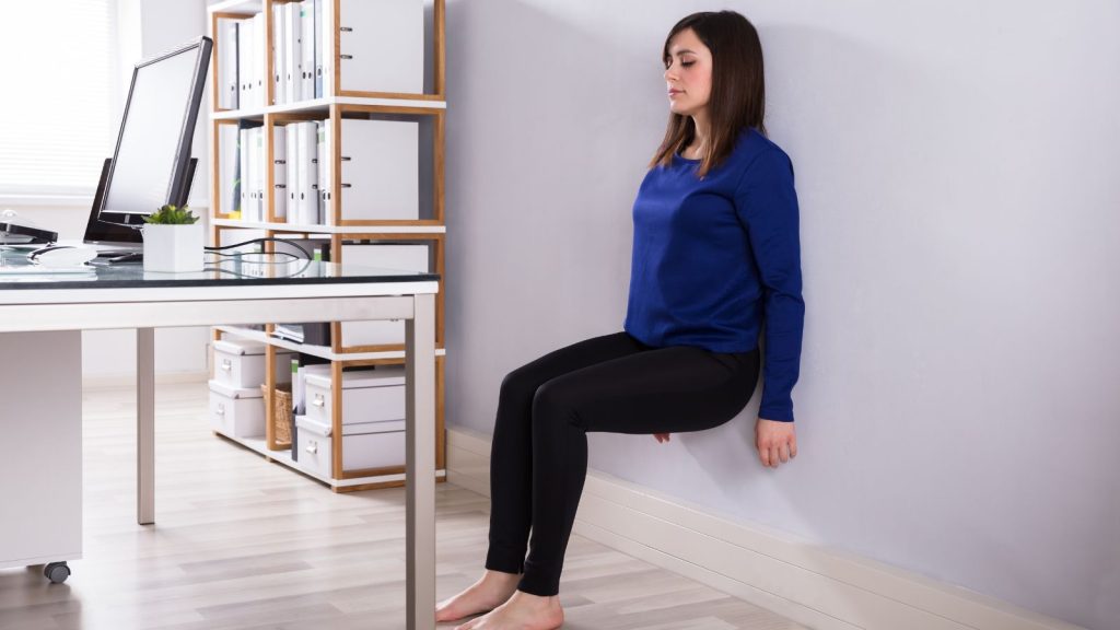 Woman Leaning On Wall Doing Workout At Workplace