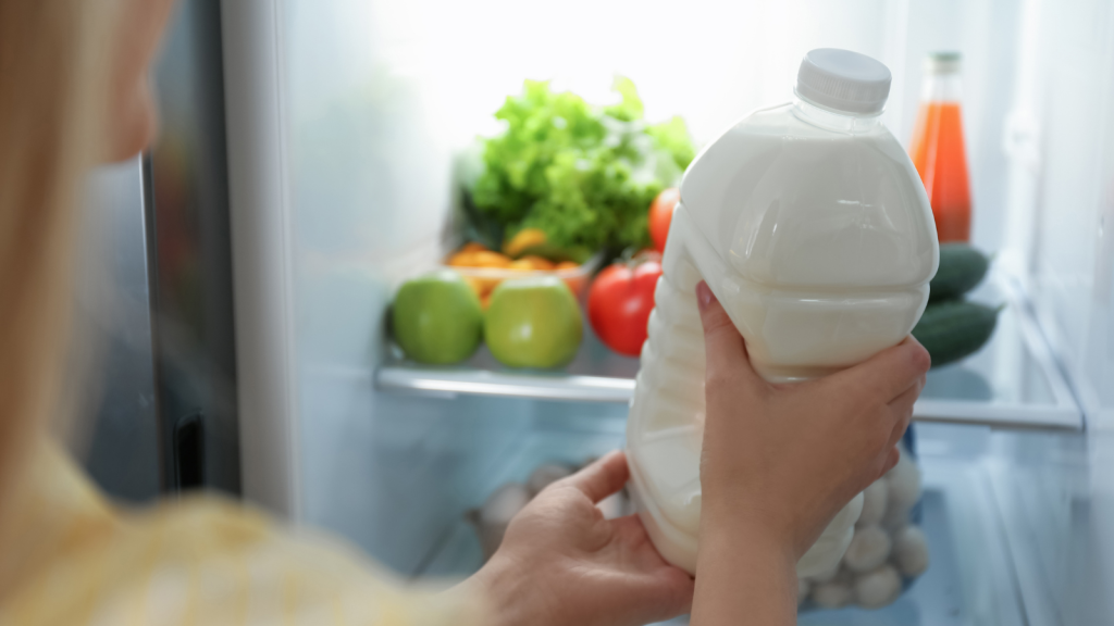 woman putting gallon of milk into refrigerator