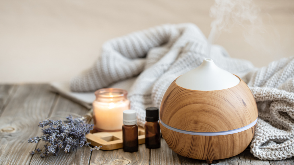 Modern aroma oil diffuser on wood surface with knitted element, candle and lavender oil on a blurred background