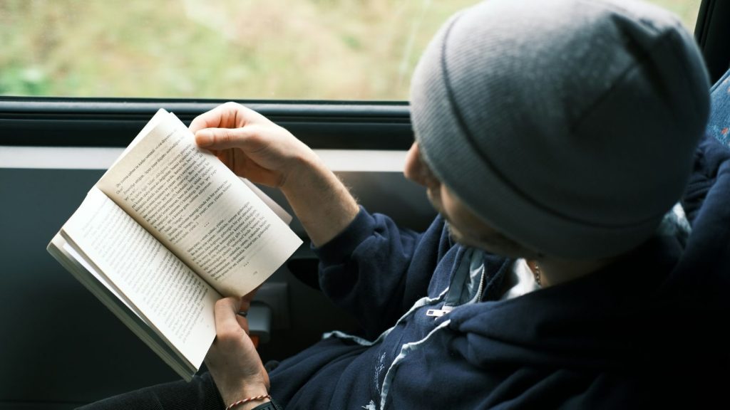 man reading a book while on a train