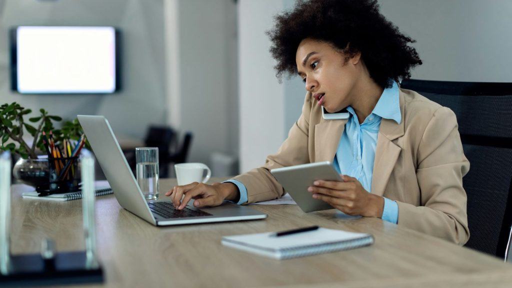 woman using a phone, laptop, and tablet