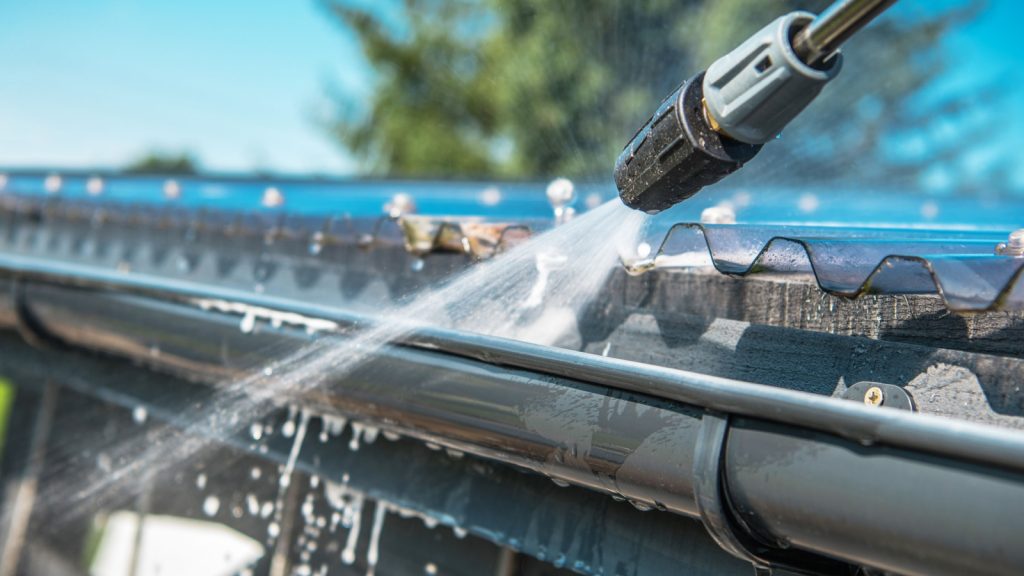 close-up shot of a pressure washer cleaning up the gutter