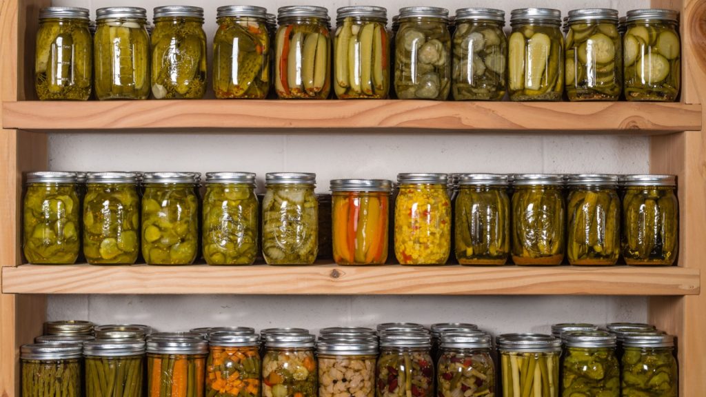 Storage shelves in pantry with homemade canned preserved fruits and vegetables