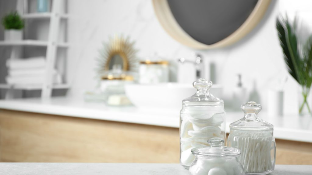 Cotton balls, swabs and pads inside jars on a in bathroom