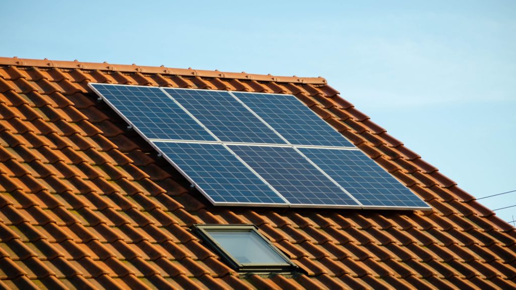 Small solar panels installation on red roof of a house.