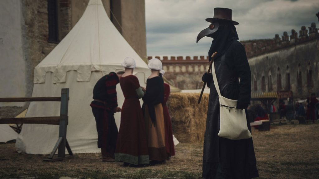 Plague doctor and people outside the quarantine booth