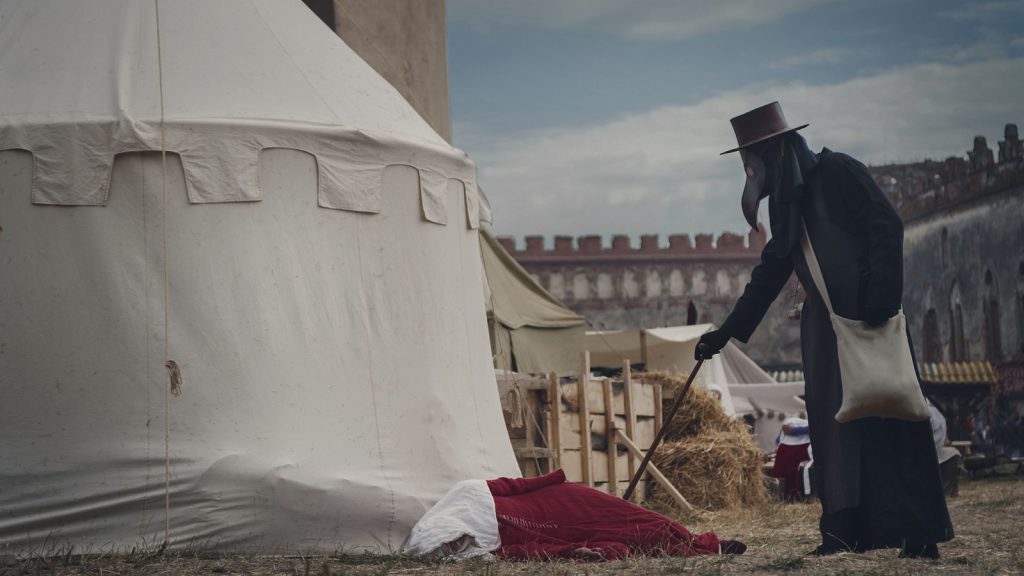 Plague doctor checking a dead woman in a ghost town