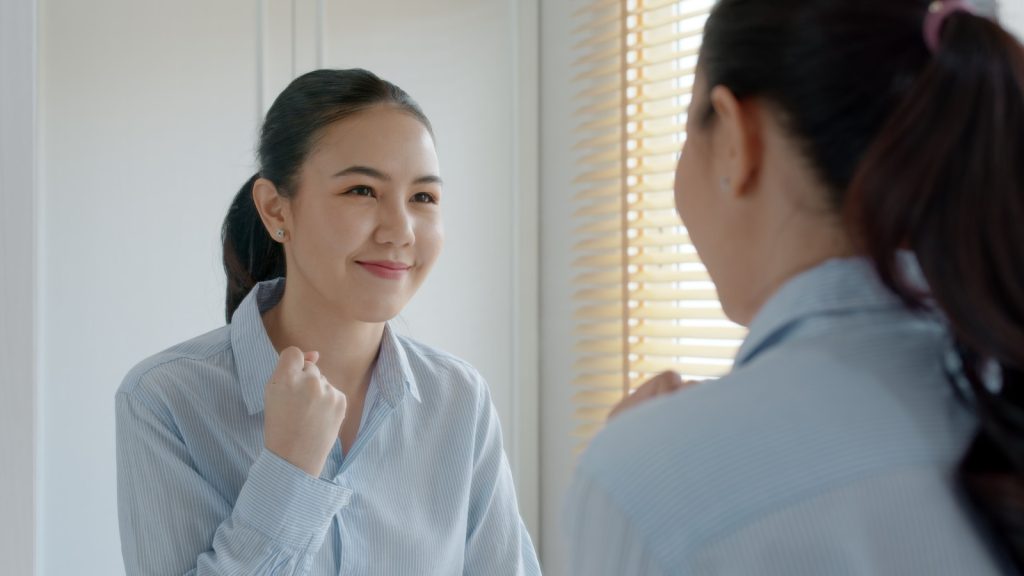 a young woman encouraging self on the mirror