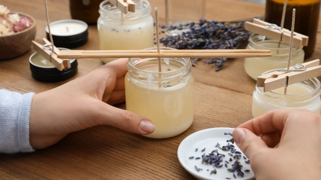 Woman making aromatic candles at wooden table.