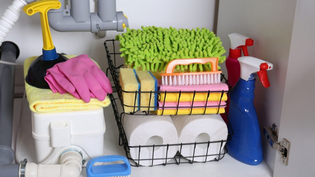 under sink cabinet with different cleaning supplies in a shelf