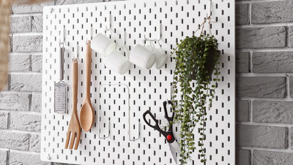 Pegboard with kitchen utensils on grey brick wall