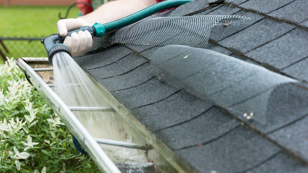 a man cleaning gutters with a water hose