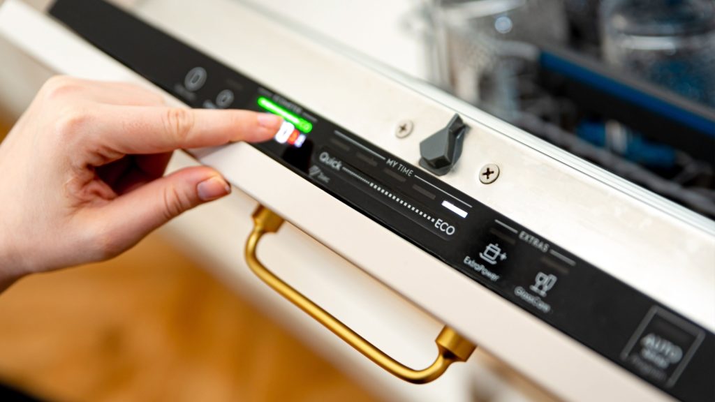 Woman choosing eco mode program on the digital control panel of the dishwasher.