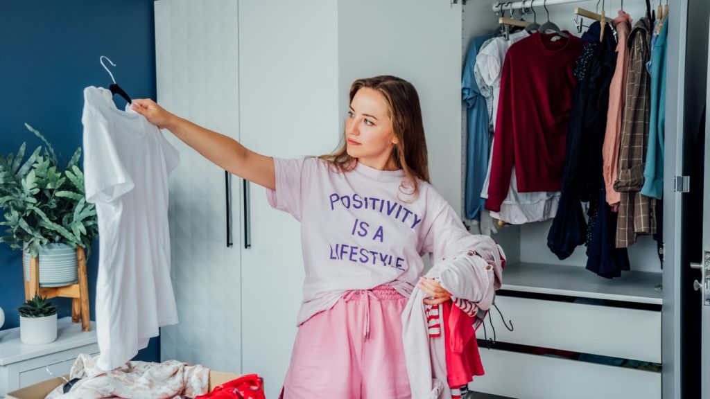 Woman selecting clothes from her wardrobe to declutter