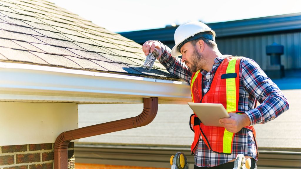 a man inspecting house gutter