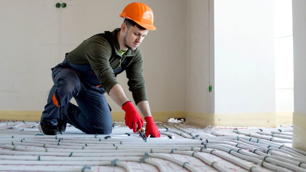 Worker is installing underfloor heating system.