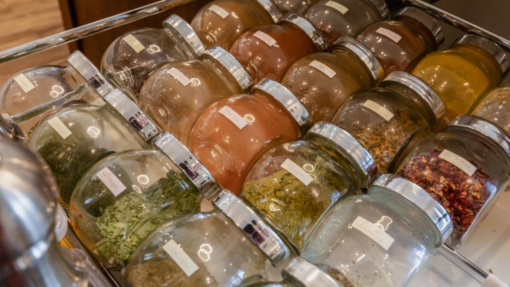 open drawer with rows of spices in small glass jar labeled aligned