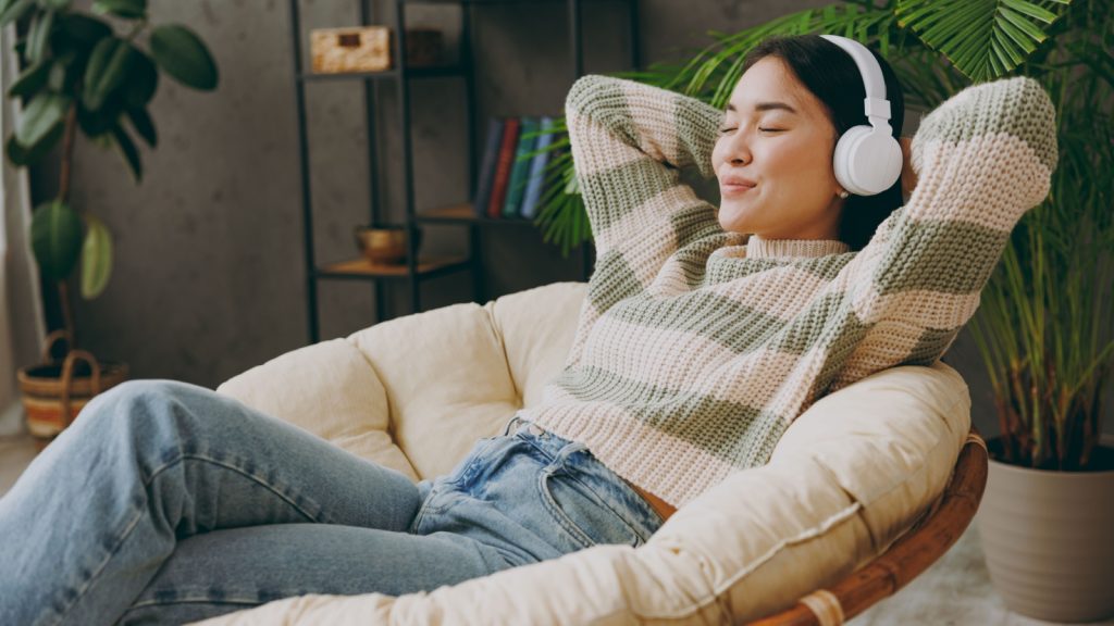 young woman relaxing with eyes closed listening to music on an armchair