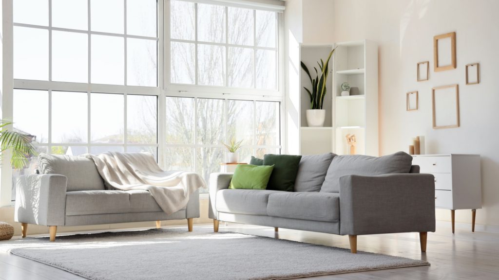 light living room with cozy grey sofas near big window in an apartment