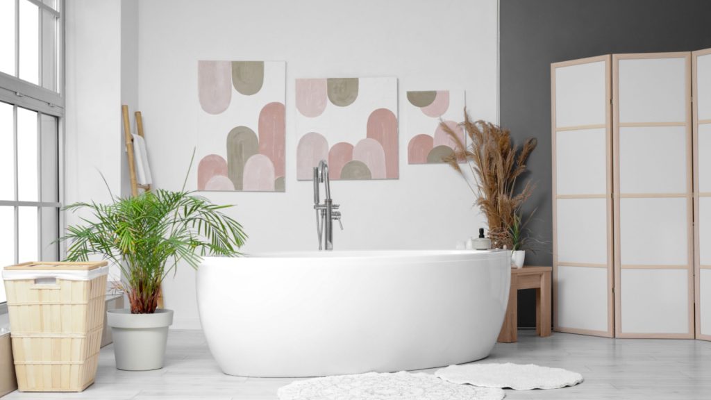 bathroom with bathtub, houseplant, and framed artwork on white wall