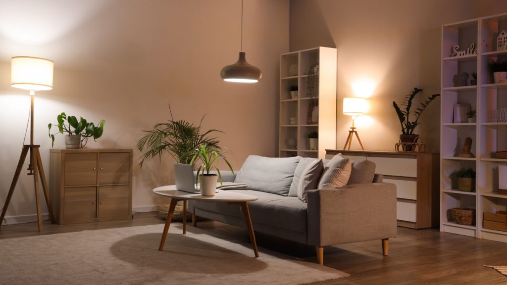 living room with sofa, shelving unit, houseplants and glowing lamps