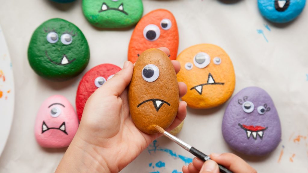 Child painting a stone for making a monster craft.