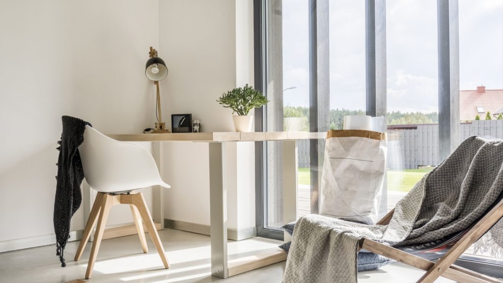 White room with deckchair, wooden desk, chair and window wall