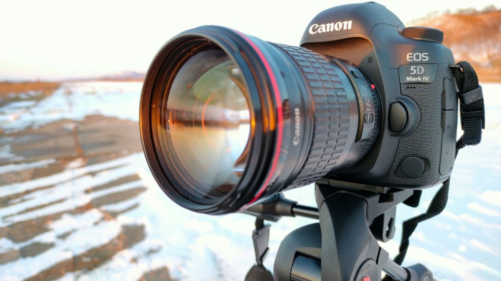 a digital camera outside on a black tripod on blurry winter background