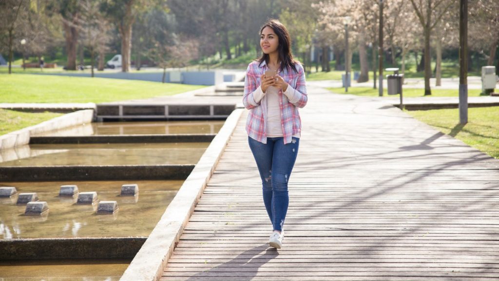 young woman walking and enjoying landscape in city park