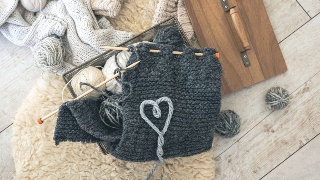 Cozy composition with a knitted element yarn and a heart made of threads.