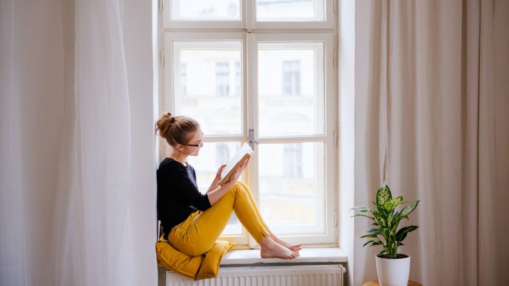 woman reading a book on a windowsill