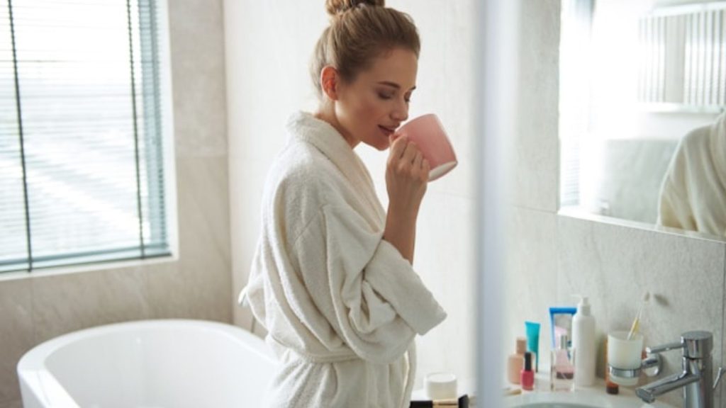 woman wearing a fluffy bathrobe with a pink mug on her hand