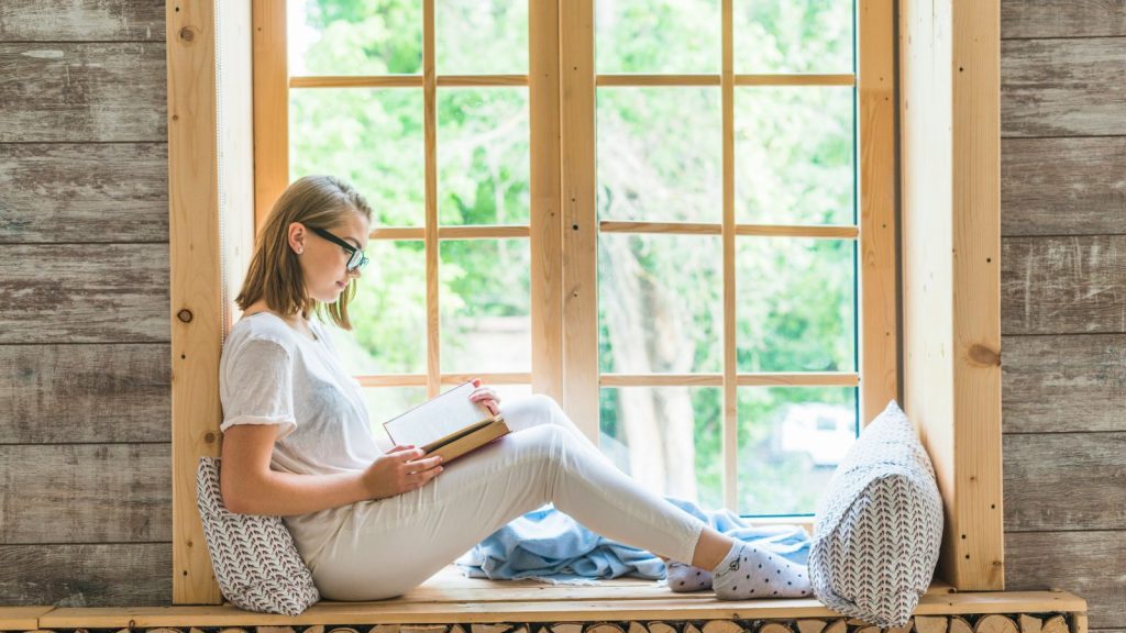 a woman reading a book on a windowsill