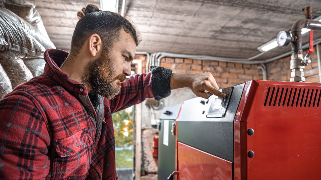 A man in a room with a solid fuel boiler.